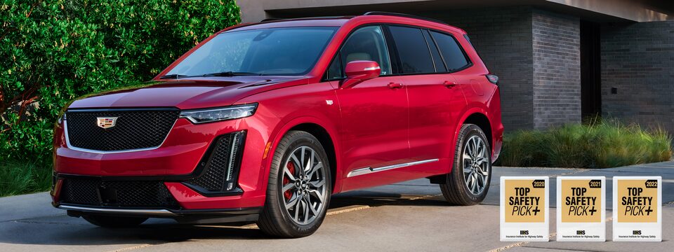 El Cadillac XT6 vibrante de colores frente a una casa lujosa
