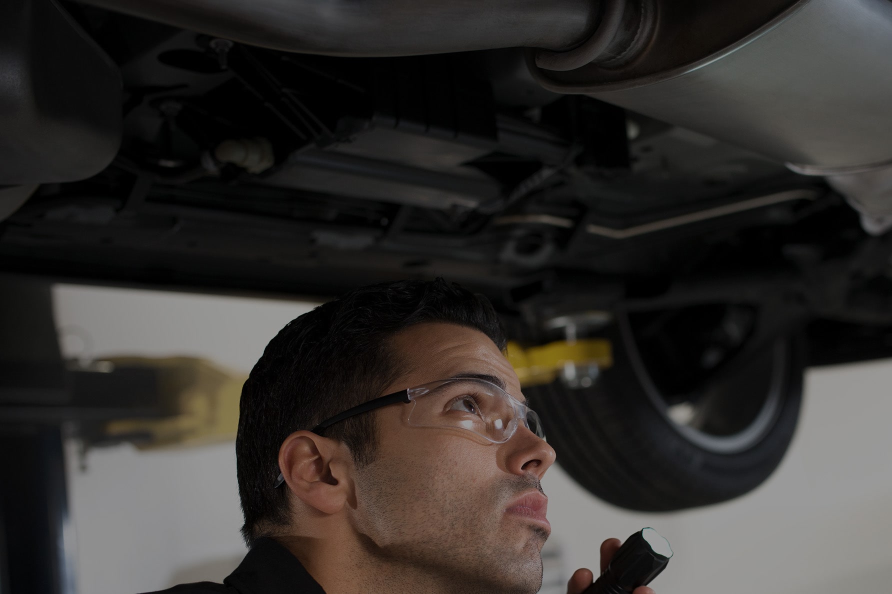 A Service Technician Looking Up at the Underside of a Vehicle