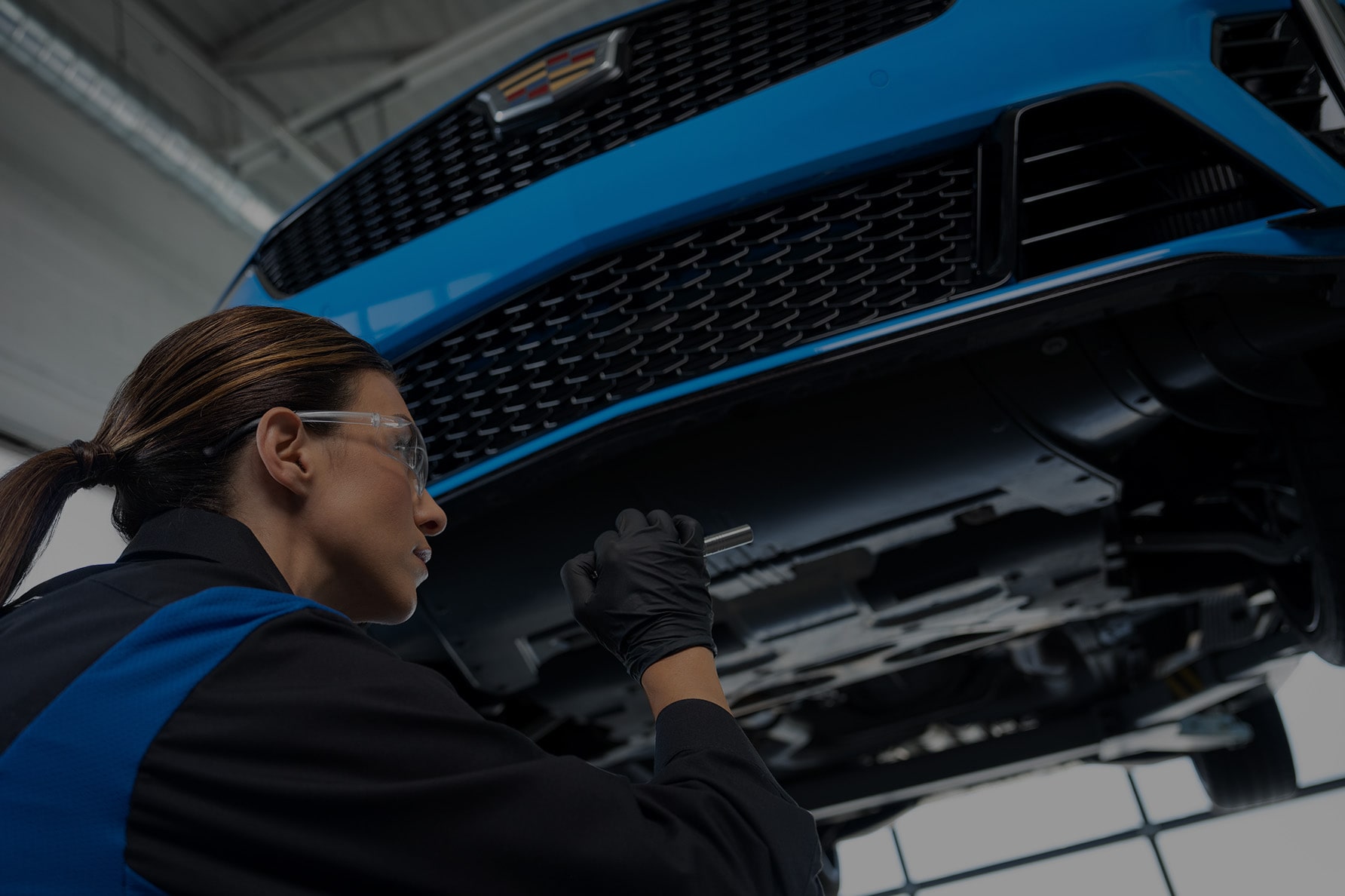 A Service Technician Working Underneath a Lifted Cadillac Vehicle