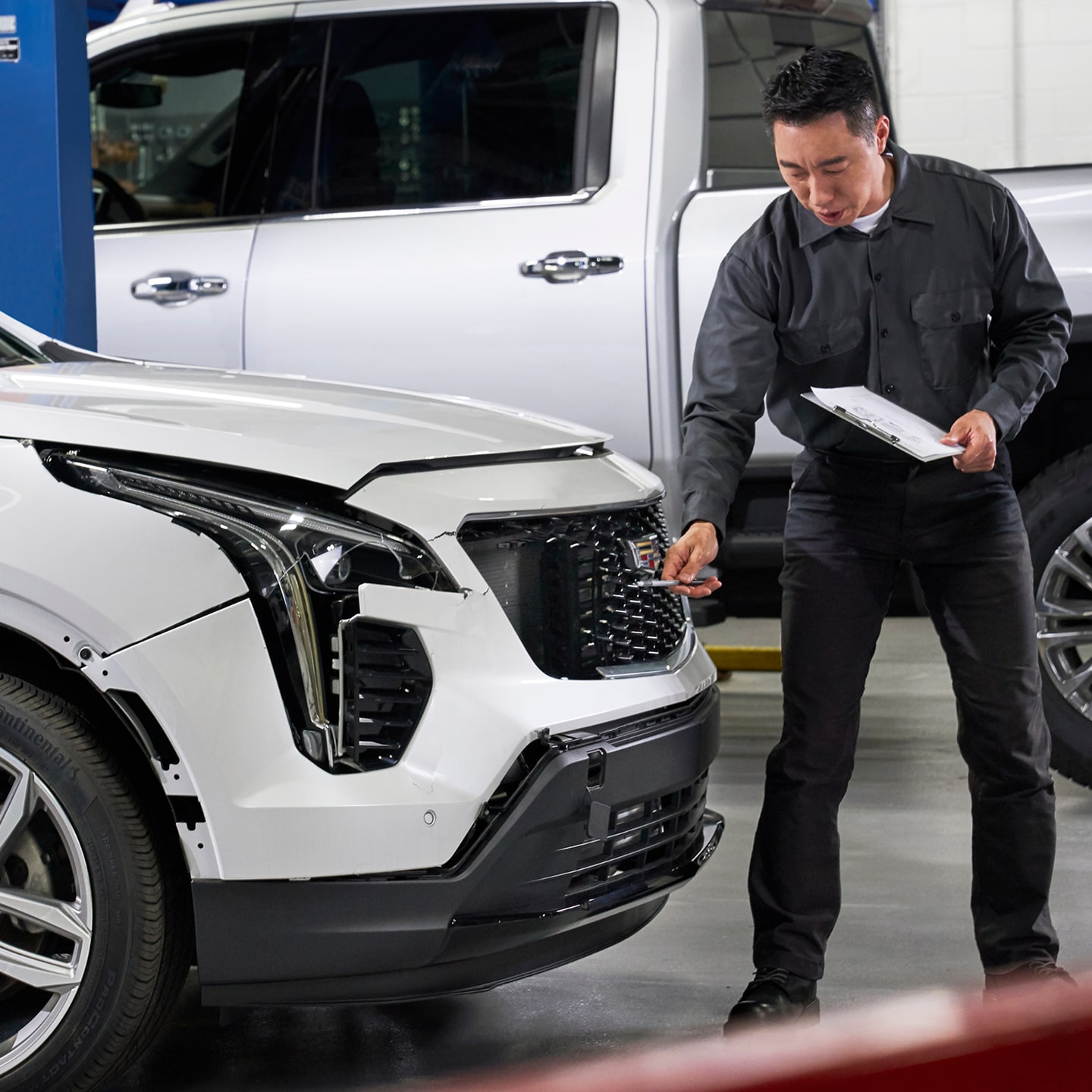 A Service Technician and Woman Inspecting the Front of a White GMC Vehicle