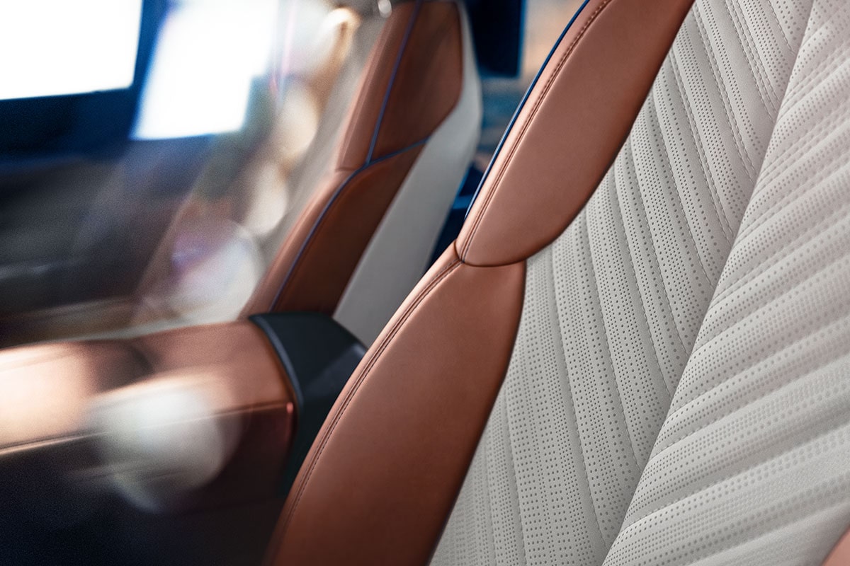 Primer plano del asiento de un vehículo Cadillac, donde se muestra el tapizado acolchado de colores claros con costuras complejas y laterales en cuero Marrón.