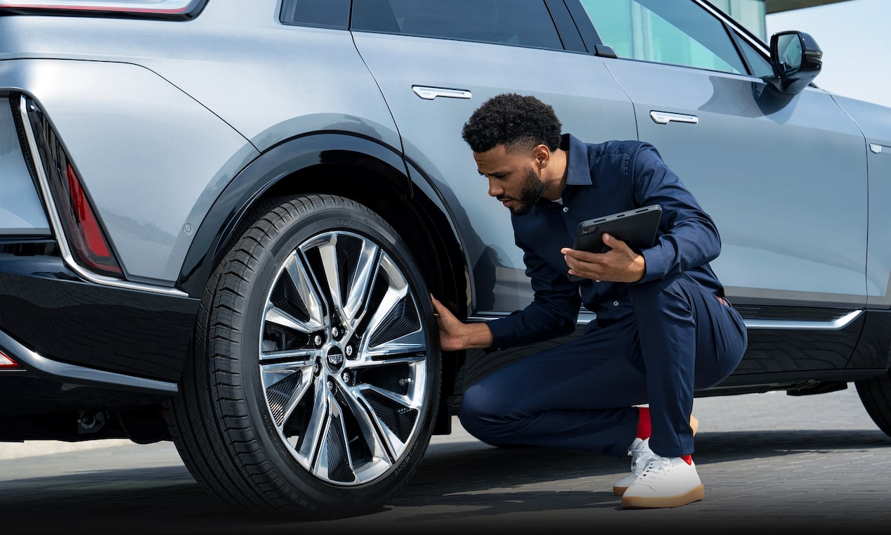 Un representante del servicio técnico de Cadillac inspecciona un neumático para comprobar si existen daños