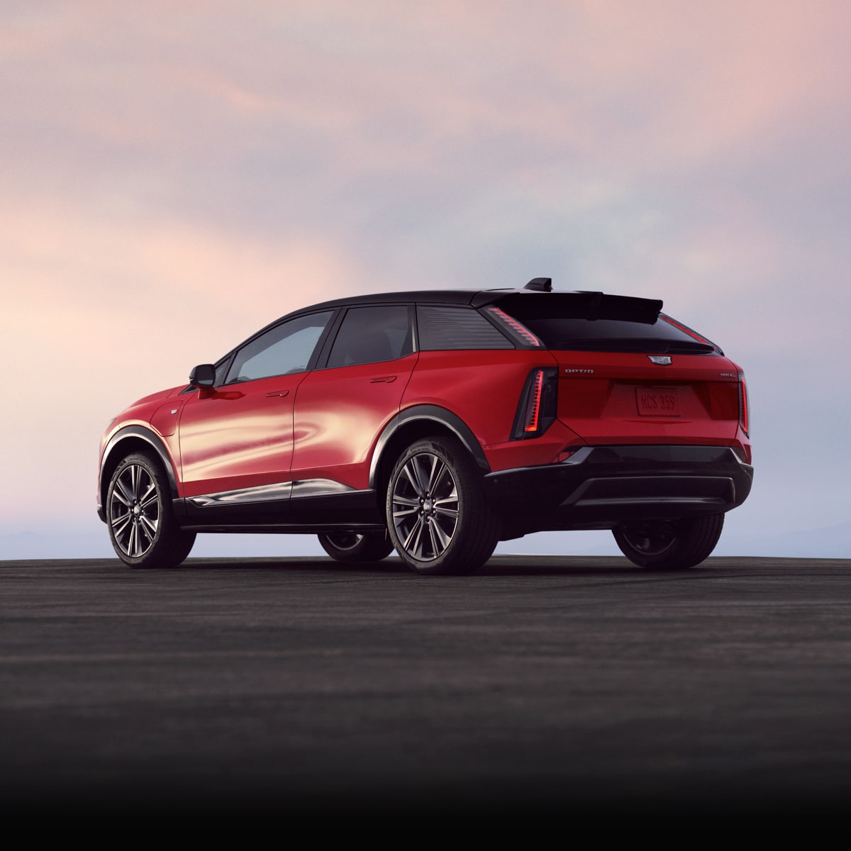Rear Three-quarters View of a Red Cadillac OPTIQ Parked Under a Beatutiful Sky