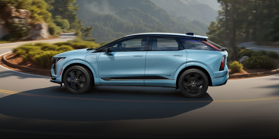 A Blue Cadillac OPTIQ-V Parked in Front of a Grey Wall.