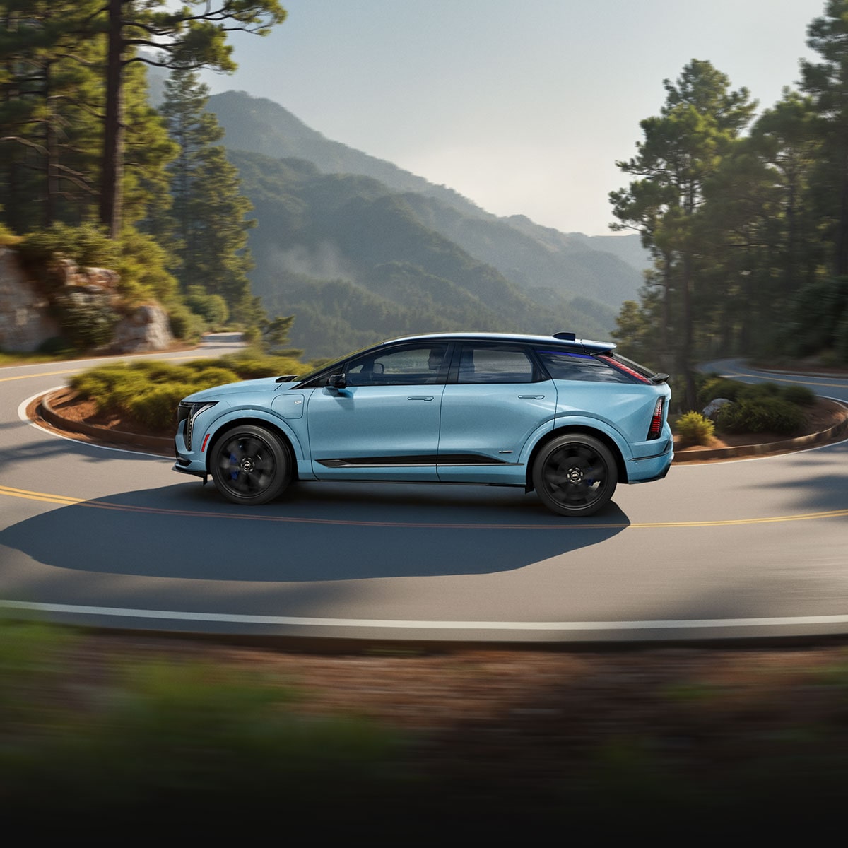 A Silver 2026 LYRIQ-V Driving Down a Highway with a Clear Blue Sky in the Background