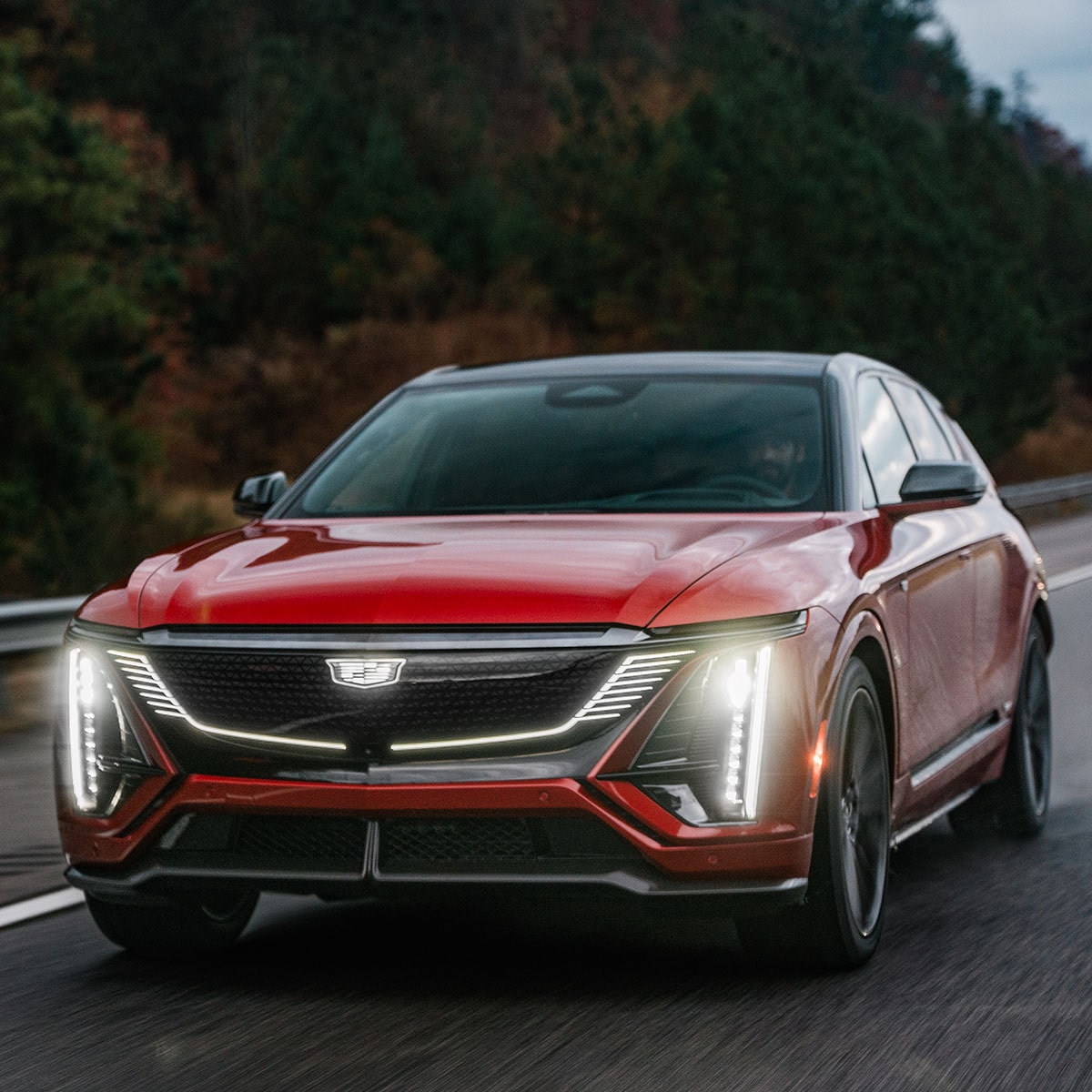 Vista delantera de Cadillac LYRIQ-V 2027 Roja circulando por un camino.