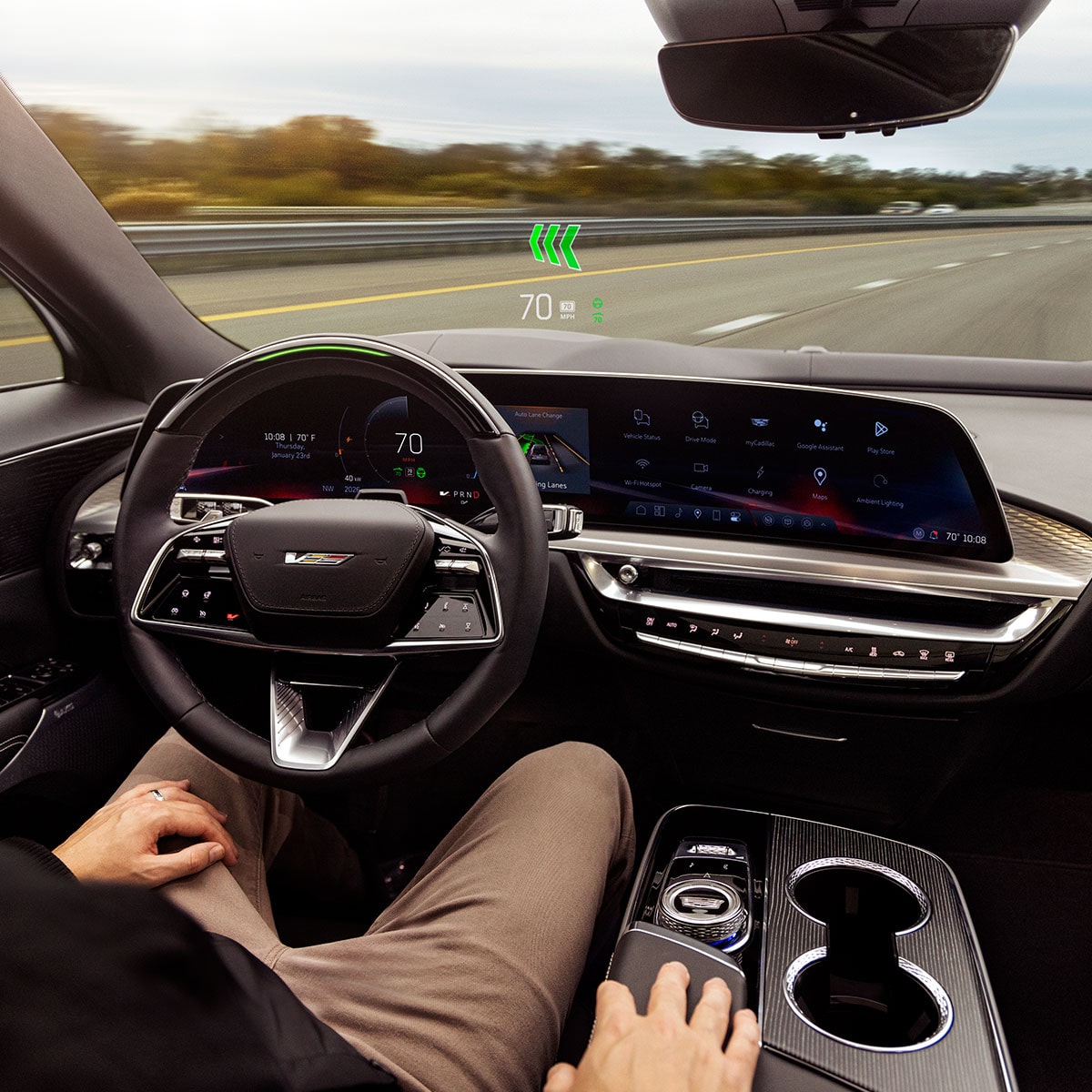 Conductora dentro de una Cadillac LYRIQ-V 2027 con Head-Up Display, panel de instrumentos digital y controles de la consola central.