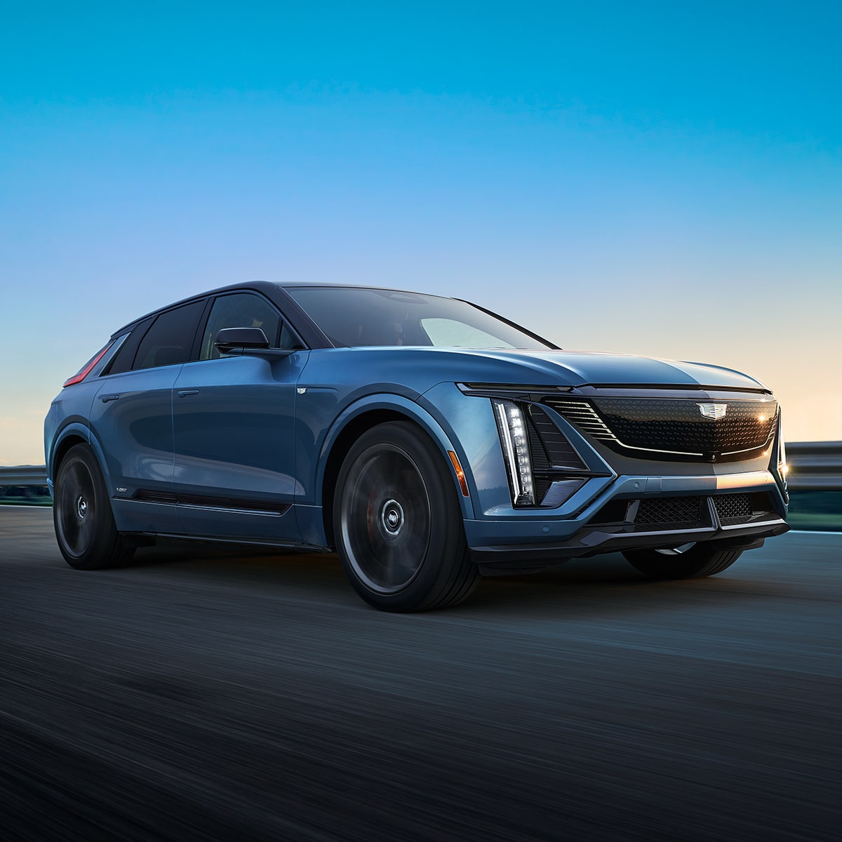 Cadillac LYRIQ 2027-V Azul circulando por un camino con iluminación LED distintiva.