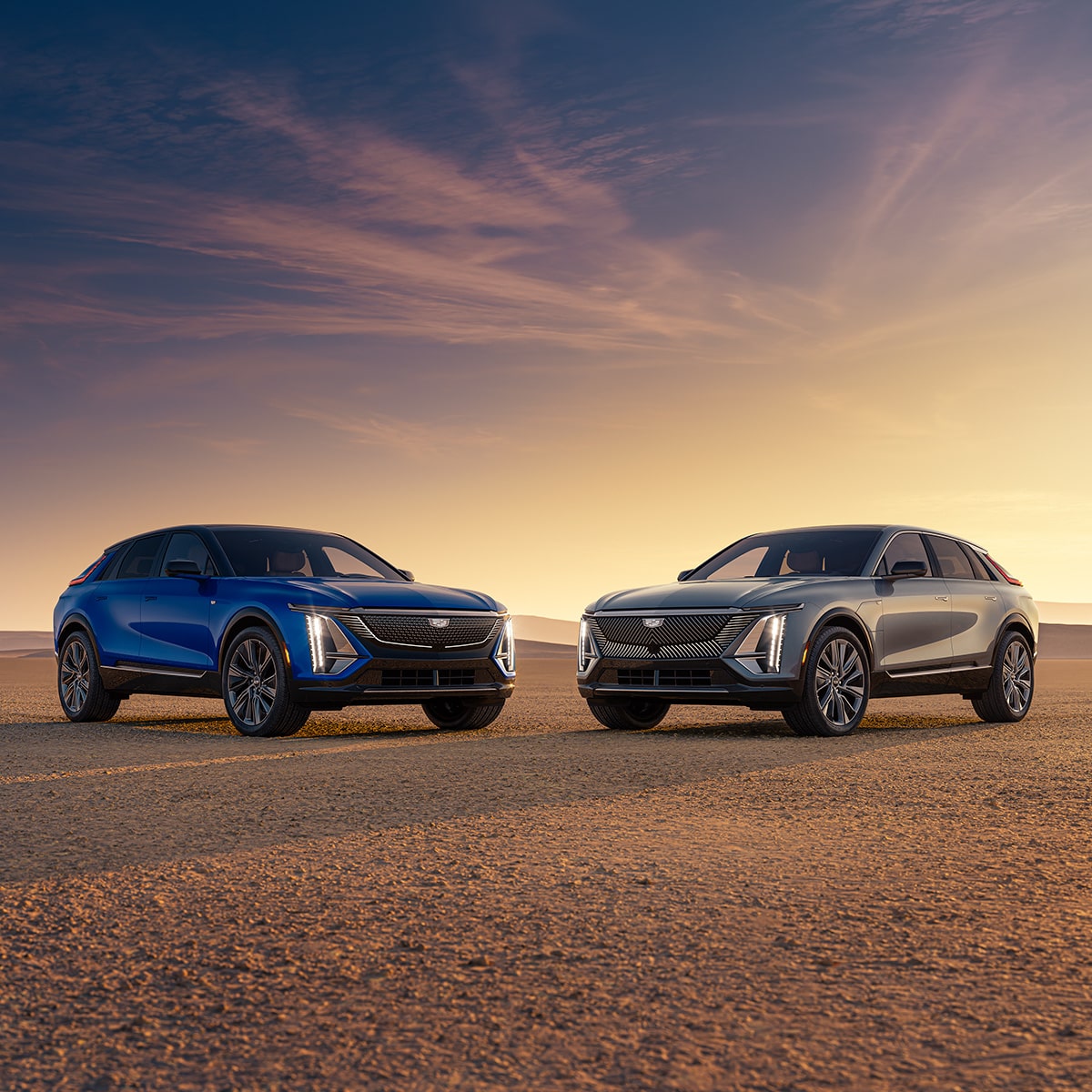Dos modelos de Cadillac LYRIQ 2027 estacionados en un paisaje desértico al atardecer.