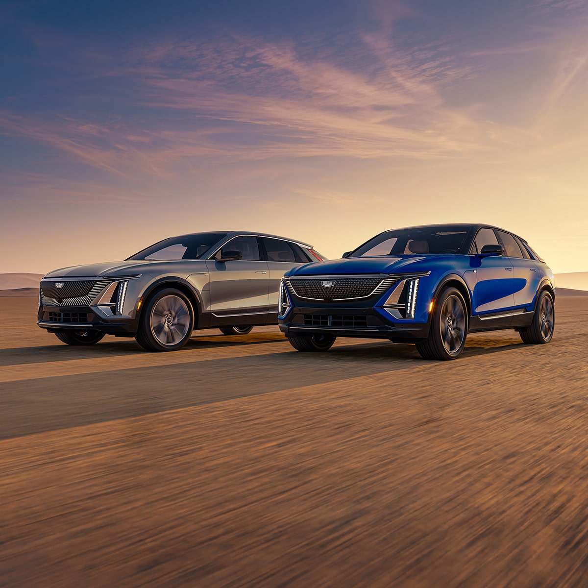 Dos modelos de Cadillac LYRIQ 2027 estacionados en un paisaje desértico al atardecer.