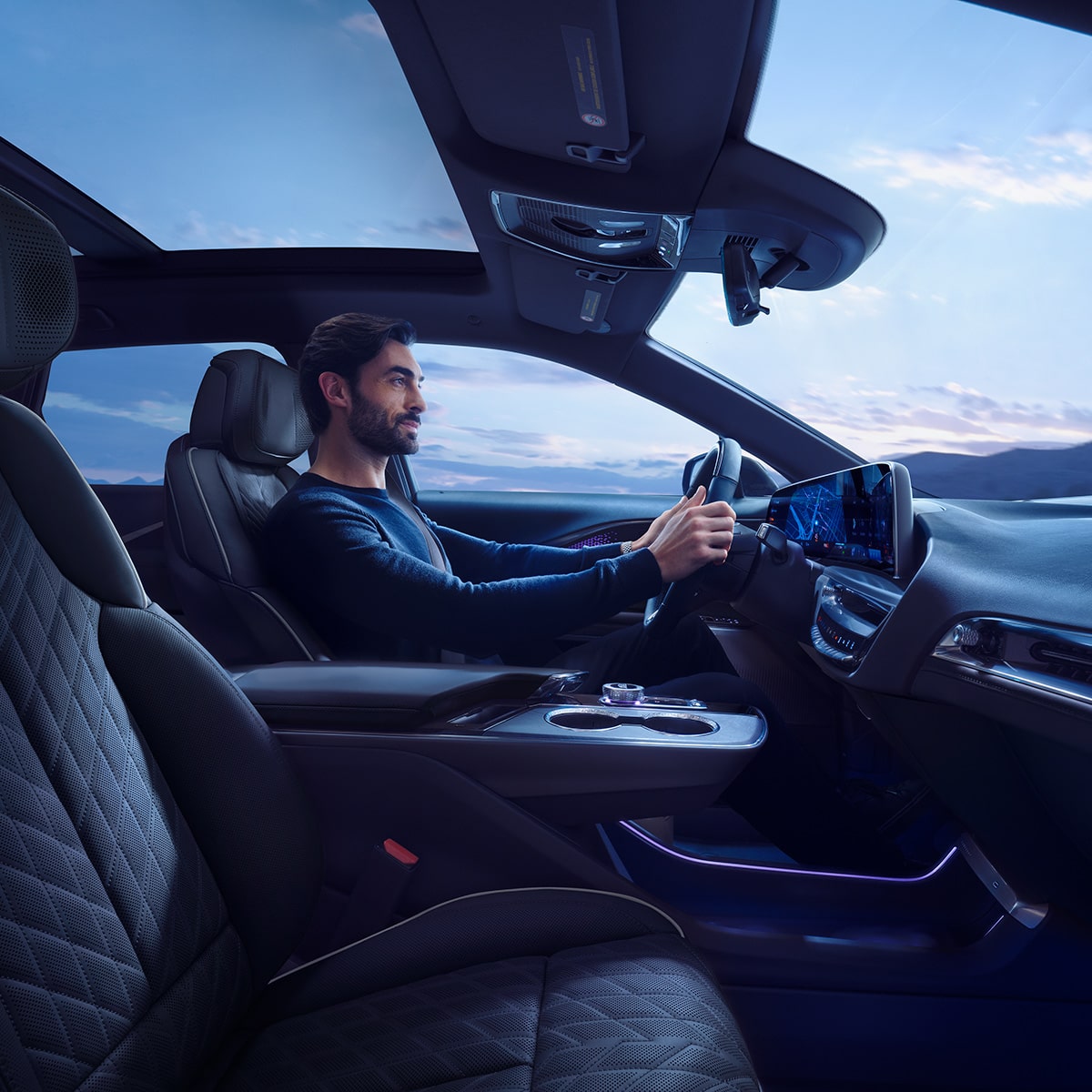Conductor dentro de una Cadillac LYRIQ 2027 con un techo de vidrio panorámico y vistas interiores de la cabina.