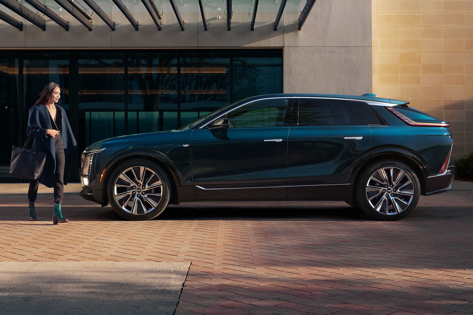 Side View of a 2027 Cadillac LYRIQ Parked Outside a Modern Building.