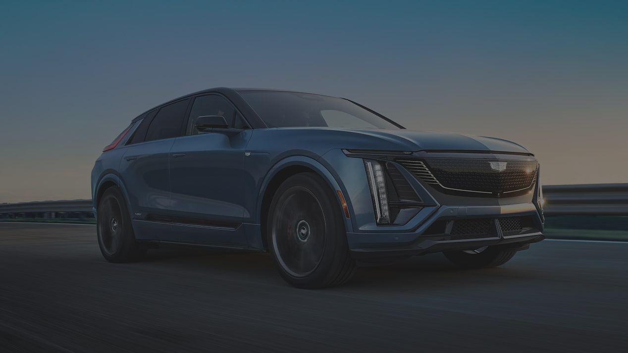 Blue 2027 Cadillac LYRIQ-V Driving on a Road at Sunset.