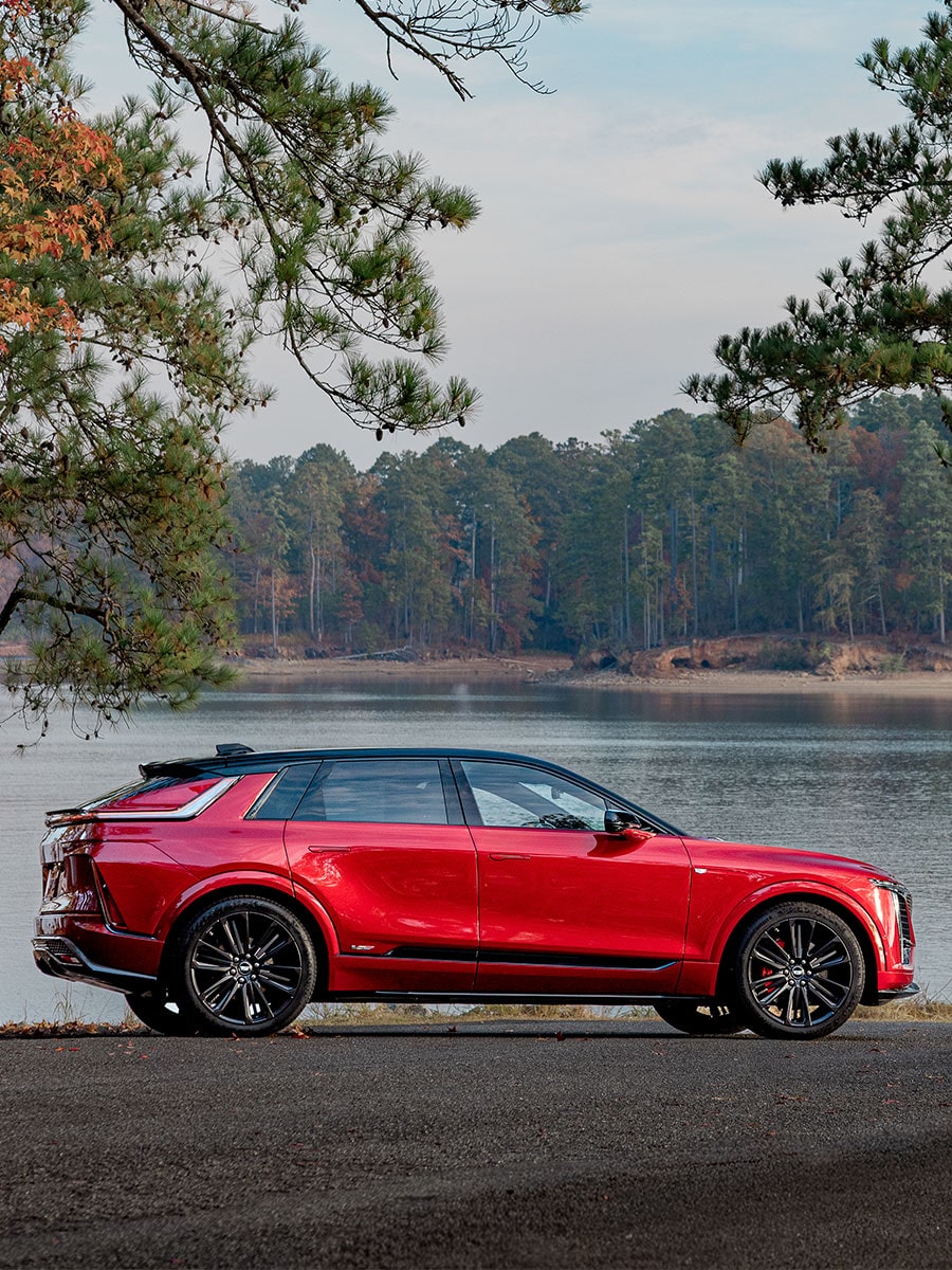 Side Profile of a Red 2027 Cadillac LYRIQ-V Parked Along a Waterfront.