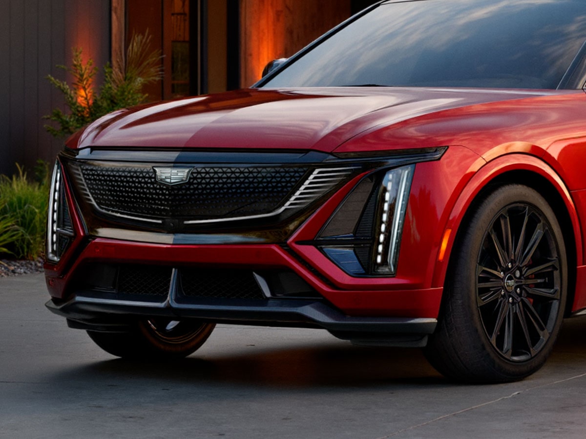 Front End of a Red 2027 Cadillac LYRIQ-V With an Illuminated Grille and Vertical LED Signature Lighting.