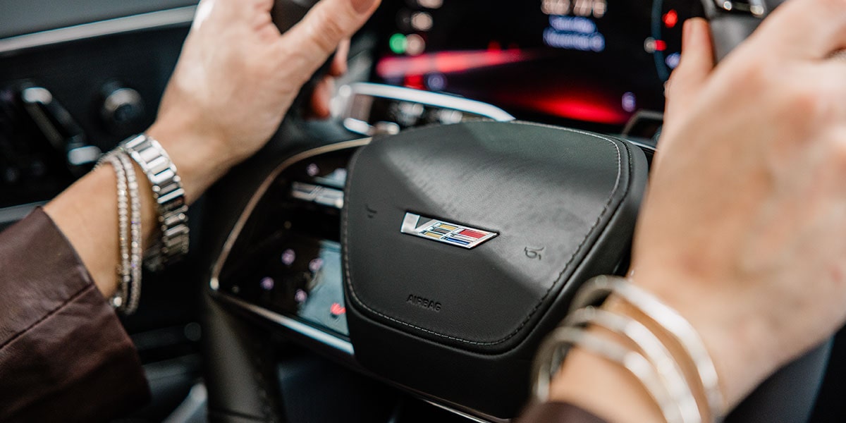 Hands on the Steering Wheel of a 2027 Cadillac LYRIQ-V With V-Series Performance Badging.