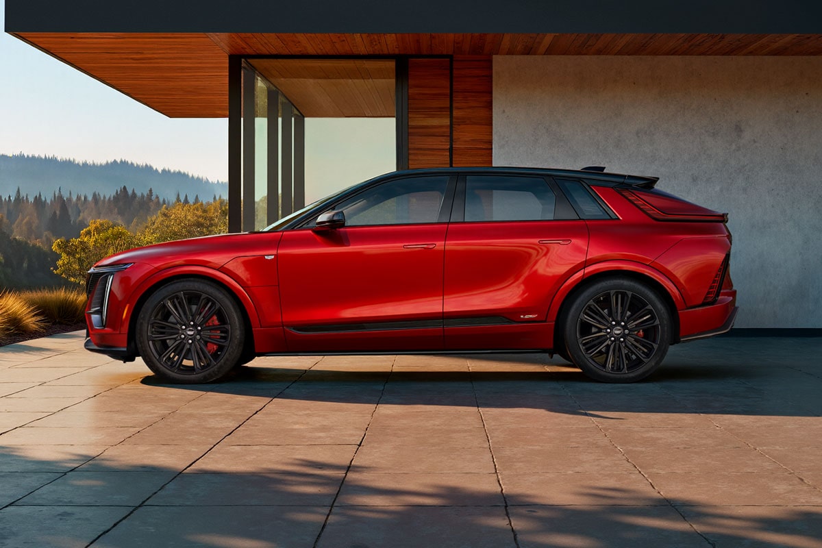 Side Profile of a Red 2027 Cadillac LYRIQ-V Parked Outside a Modern Home.