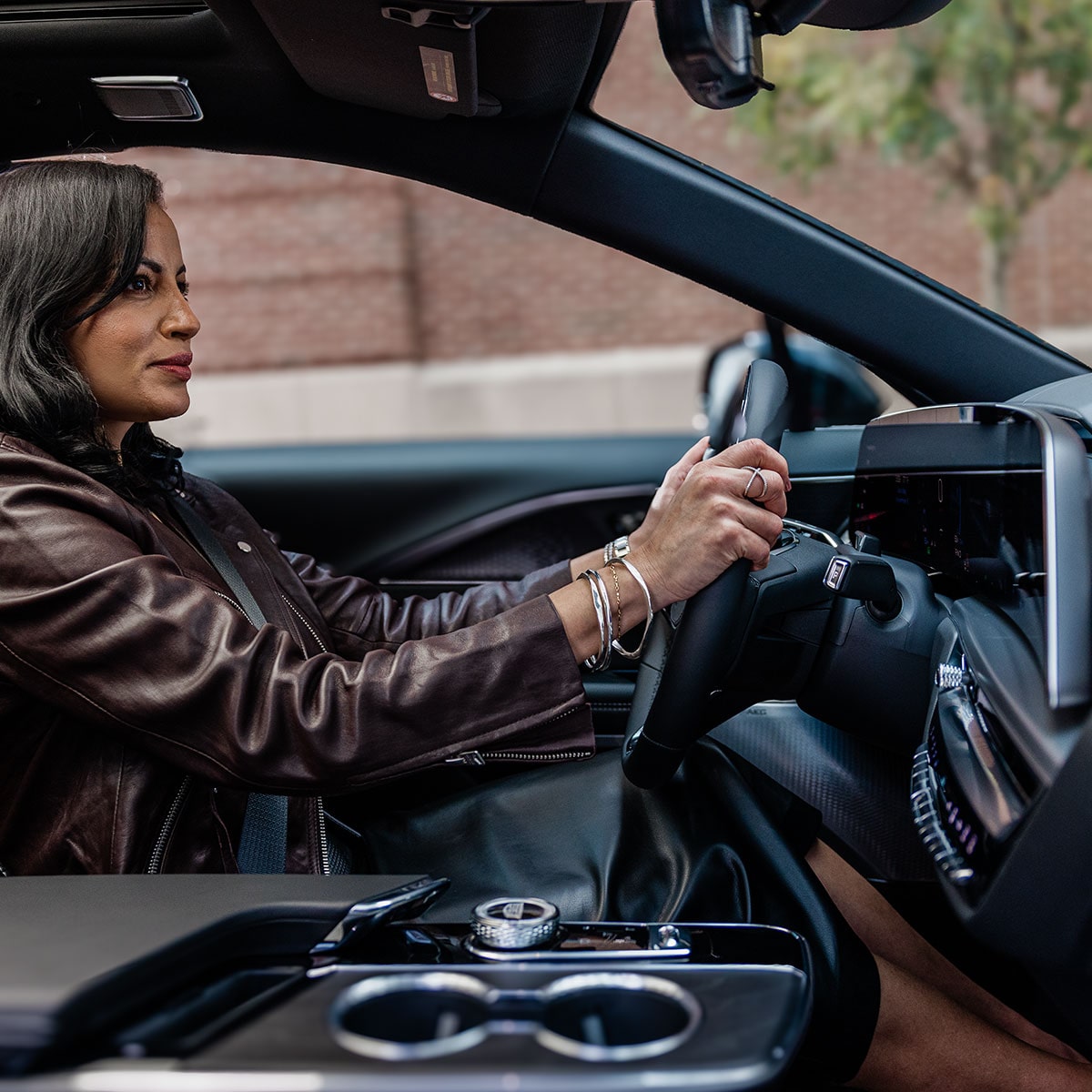 Driver Inside a 2027 Cadillac LYRIQ-V With a Digital Display and Center Console Controls.