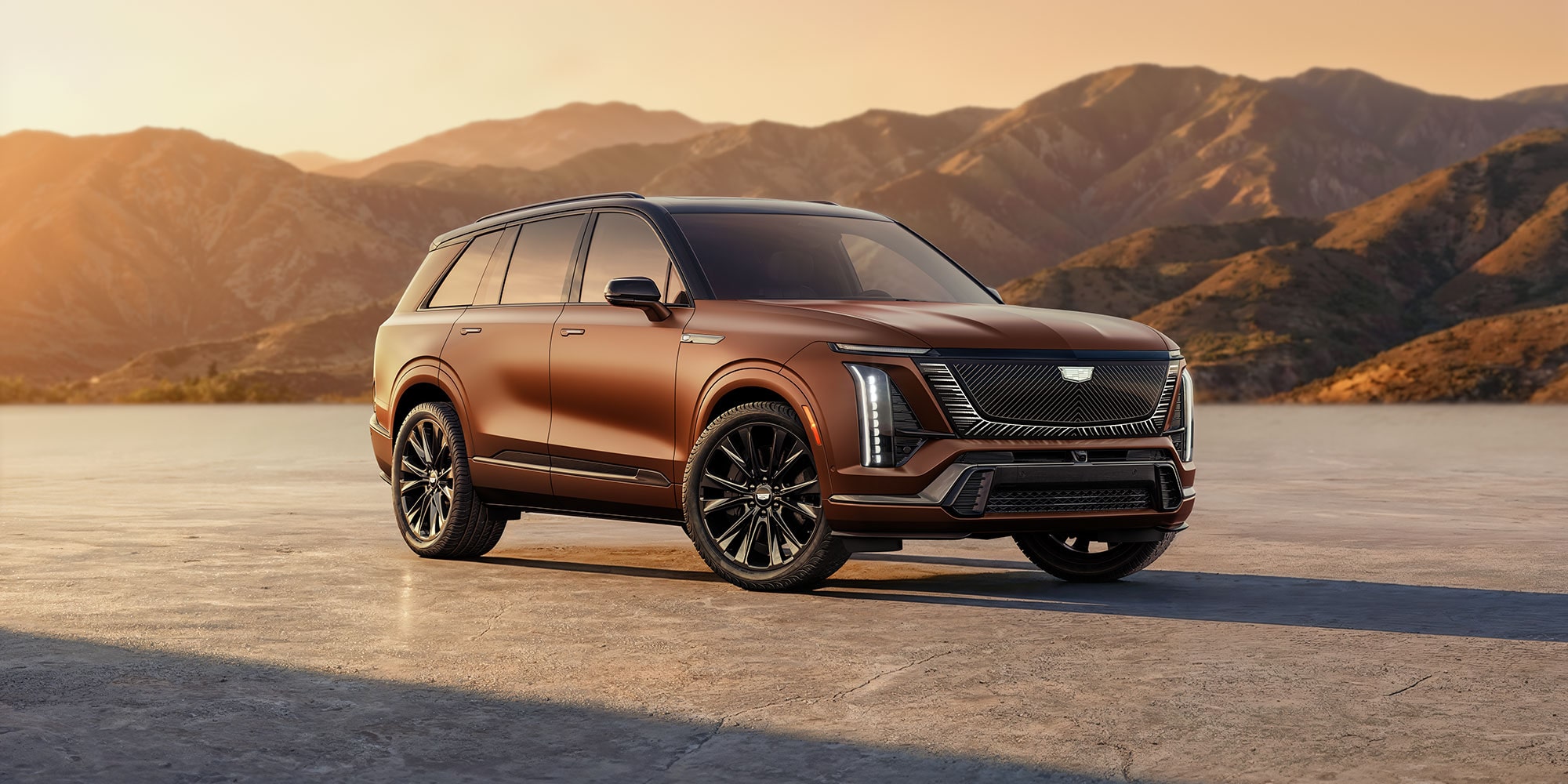 Three-quarter Passenger Side View of the 2027 Cadillac VISTIQ Parked Outlooking the Mountains During a Sunset