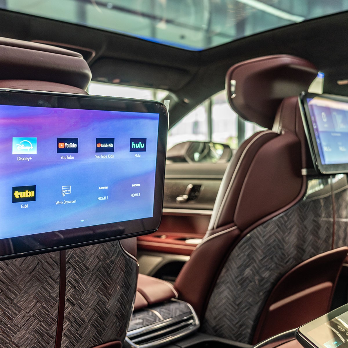 A View of the Rear Seats in the Cadillac CELESTIQ, Featuring Brown Leather, Textured Seatbacks, and Dual Infotainment Screens Displaying App Icons.