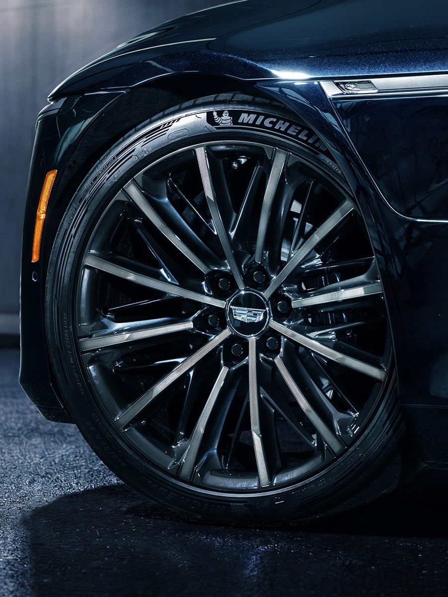 A Close-Up View of a Black Multi-Spoke Wheel and Front Fender of a Cadillac CELESTIQ With Water Droplets Across the Glossy Exterior Surface.