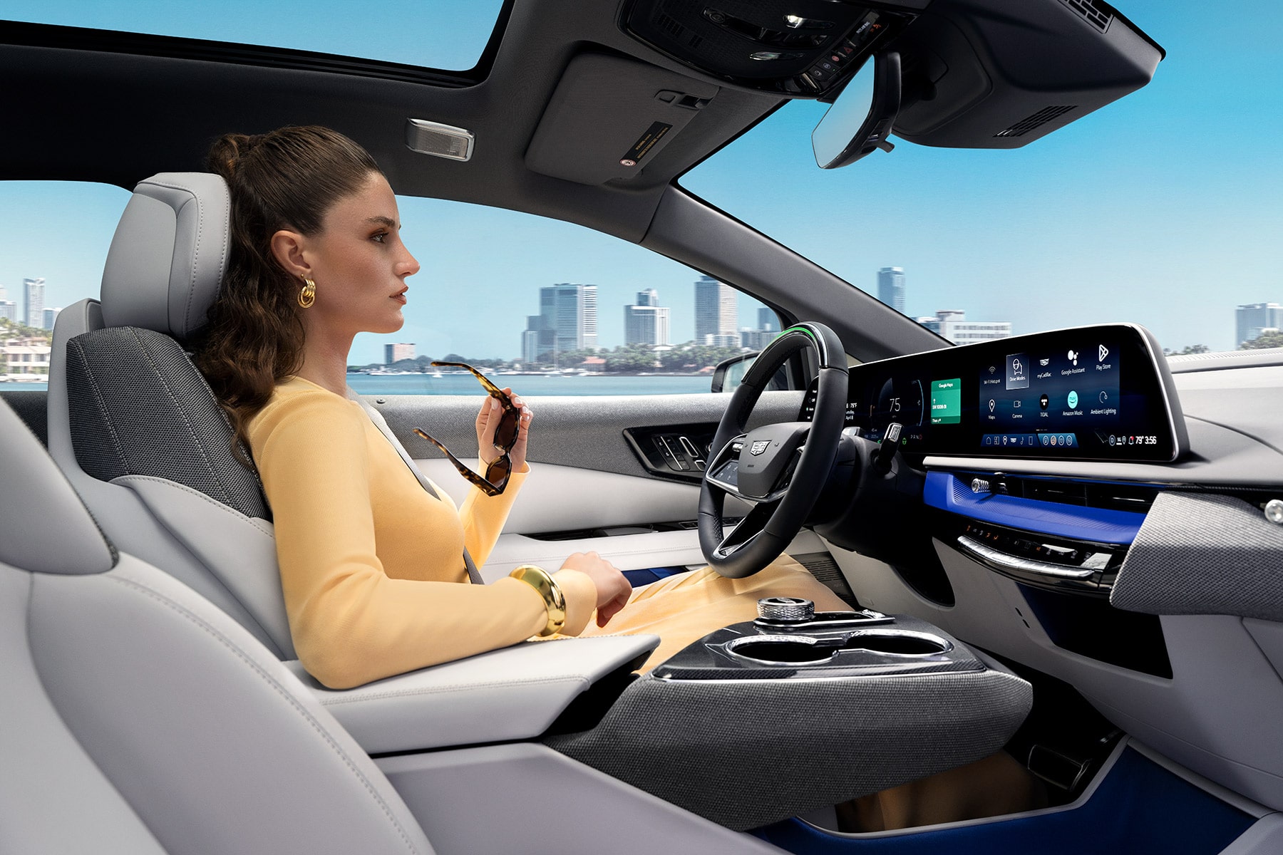 Passenger View of a Woman Driving a Cadillac OPTIQ Past the City While Utilizing Super Cruise Hands-free Technology
