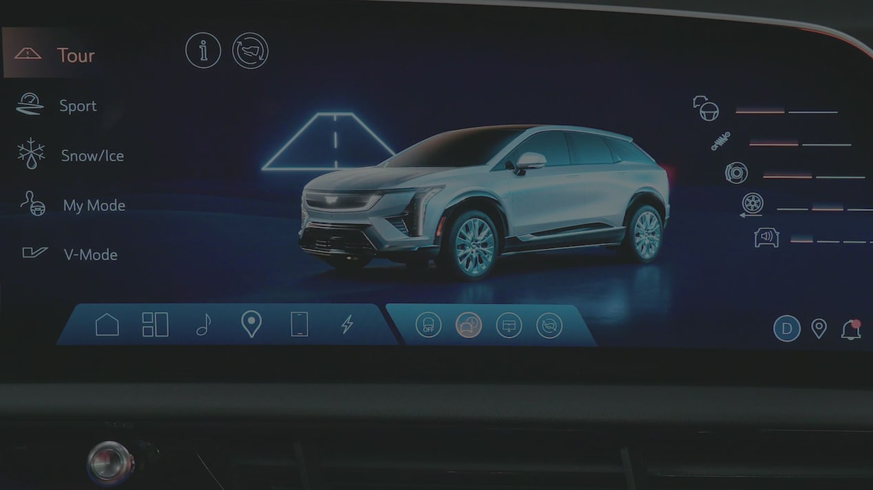 A Cadillac OPTIQ Infotainment Screen Displaying Drive Mode Options Beside a Rendered Image Of a Silver Cadillac SUV.
