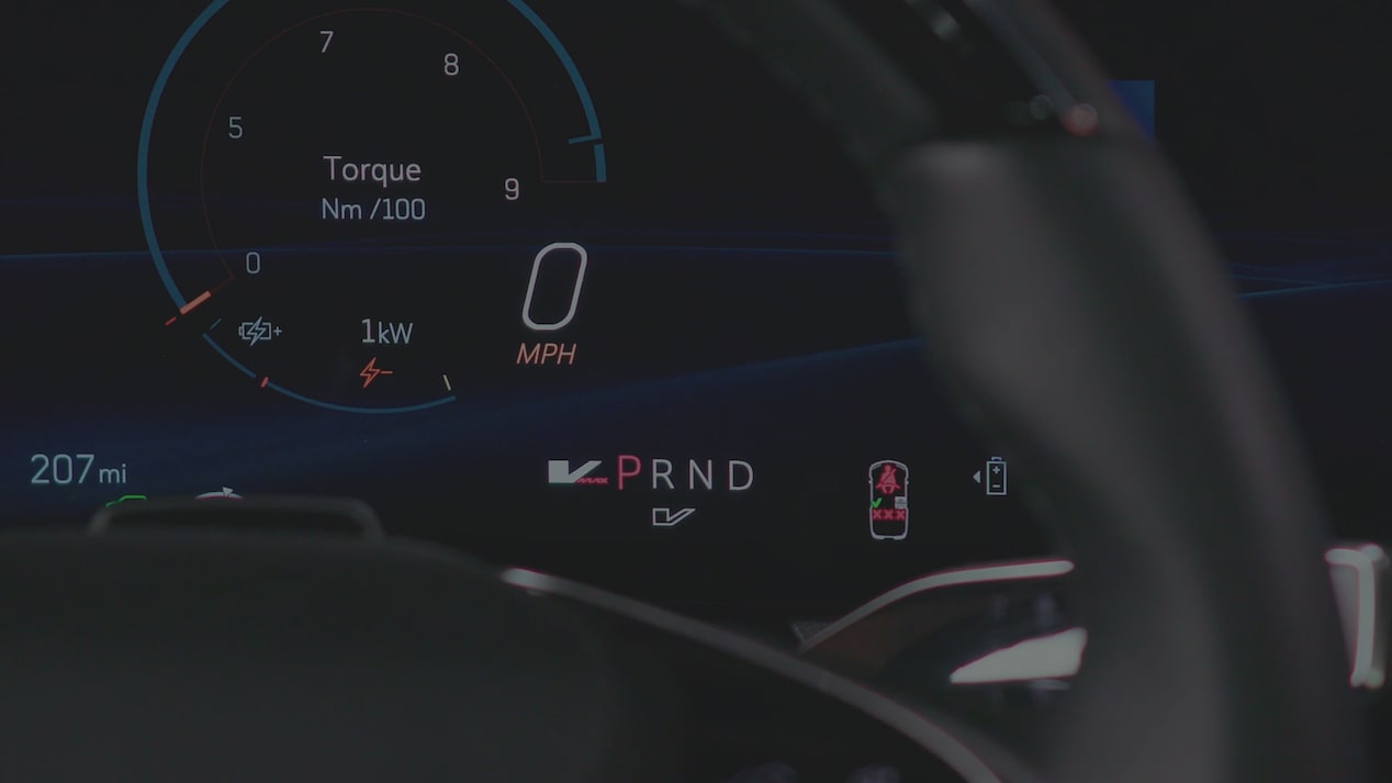 A Digital Cadillac OPTIQ Driver Display Showing Torque Output, Speed, And PRND Gear Indicators Partially Framed By the Steering Wheel.