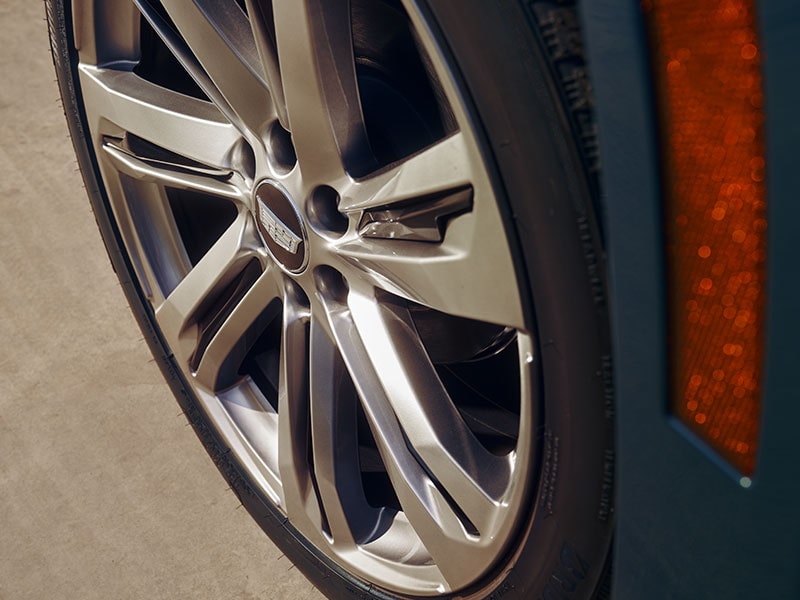 A Close up of a Cadillac Wheel with a Gray Multi-spoke Design and a Visible Amber Side Marker Light