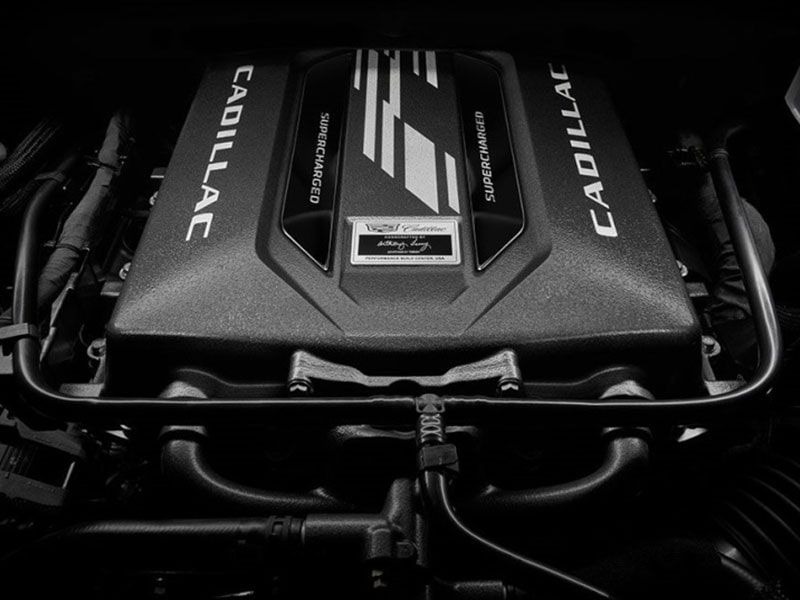 A Close up of the Front Grille and Headlight of a Red Cadillac SUV Featuring the Colorful Cadillac Emblem