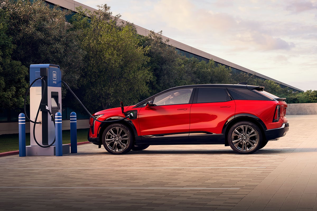 Profile View of a Red Cadillac OPTIQ Charging at a GM EVgo Charging Station in a Public Parking Lot