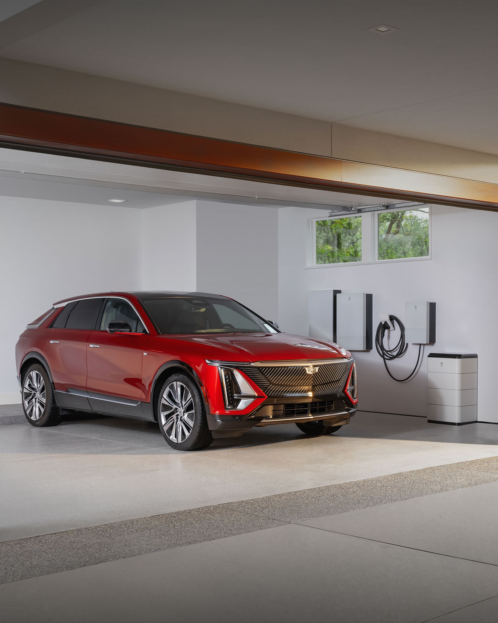 A Red Cadillac VISTIQ Parked in a Garage Next to a GM Energy Home System