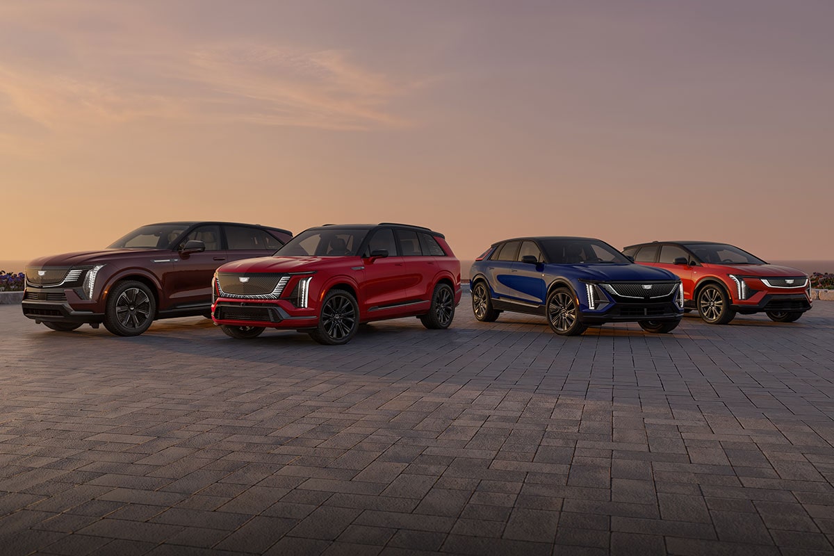 Four Cadillac Electric Vehicles are Parked on a Paved Overlook with an Ocean Sunset