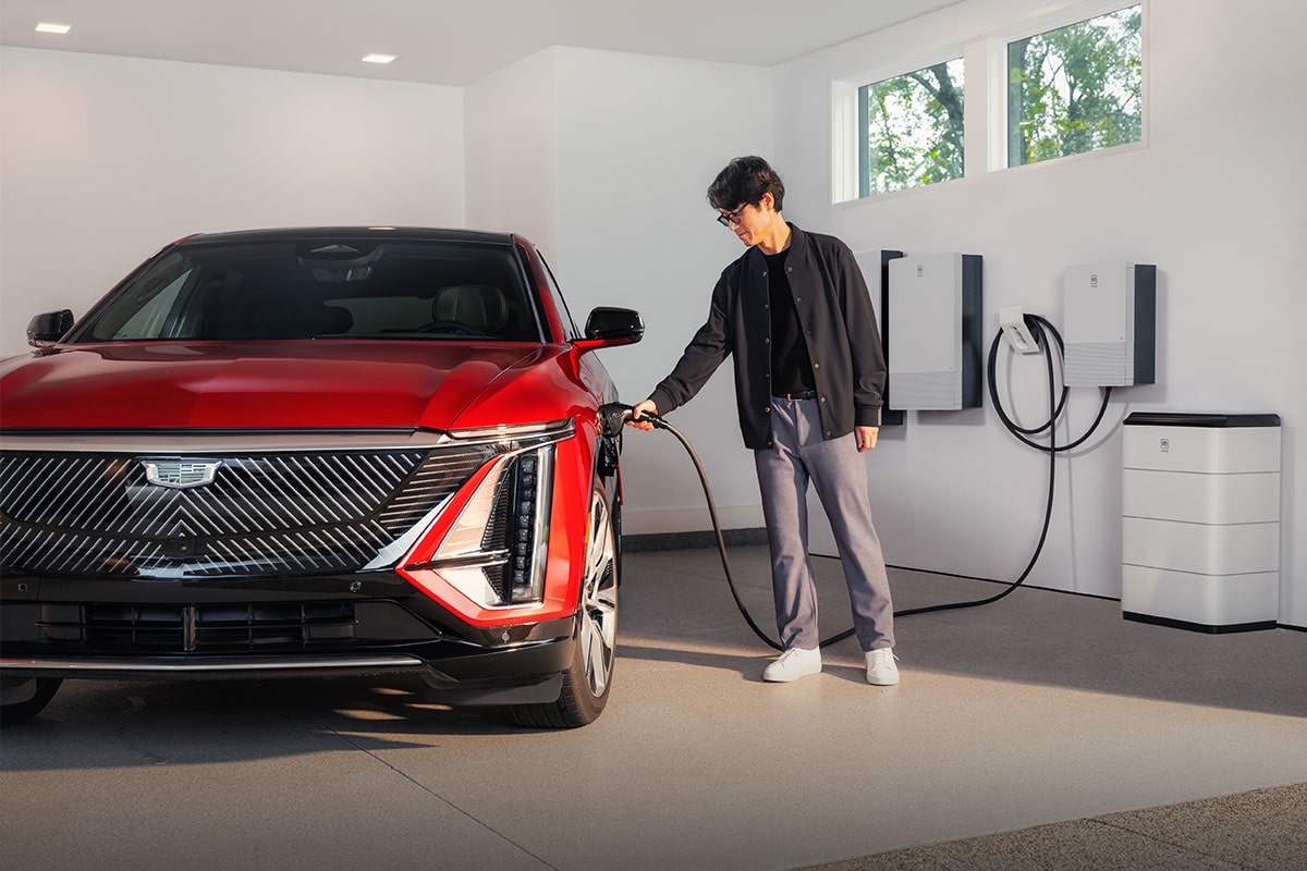 A Man Plugging in an EV Charger into a Cadillac OPTIQ in a Garage