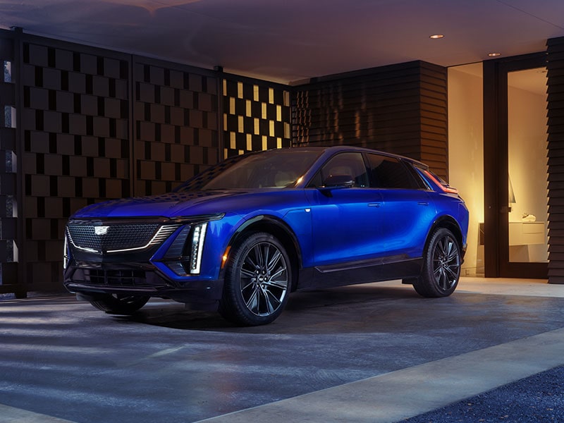 A Blue Cadillac LYRIQ Parked Next to a GM Energy Home Charger in a Luxurious Garage