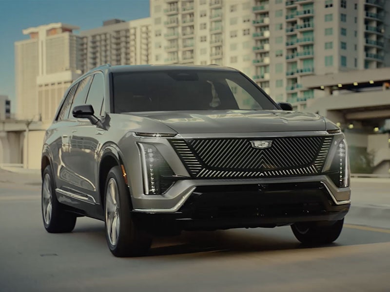 Front View of a Gray Cadillac VISTIQ Electric SUV Driving Through the City