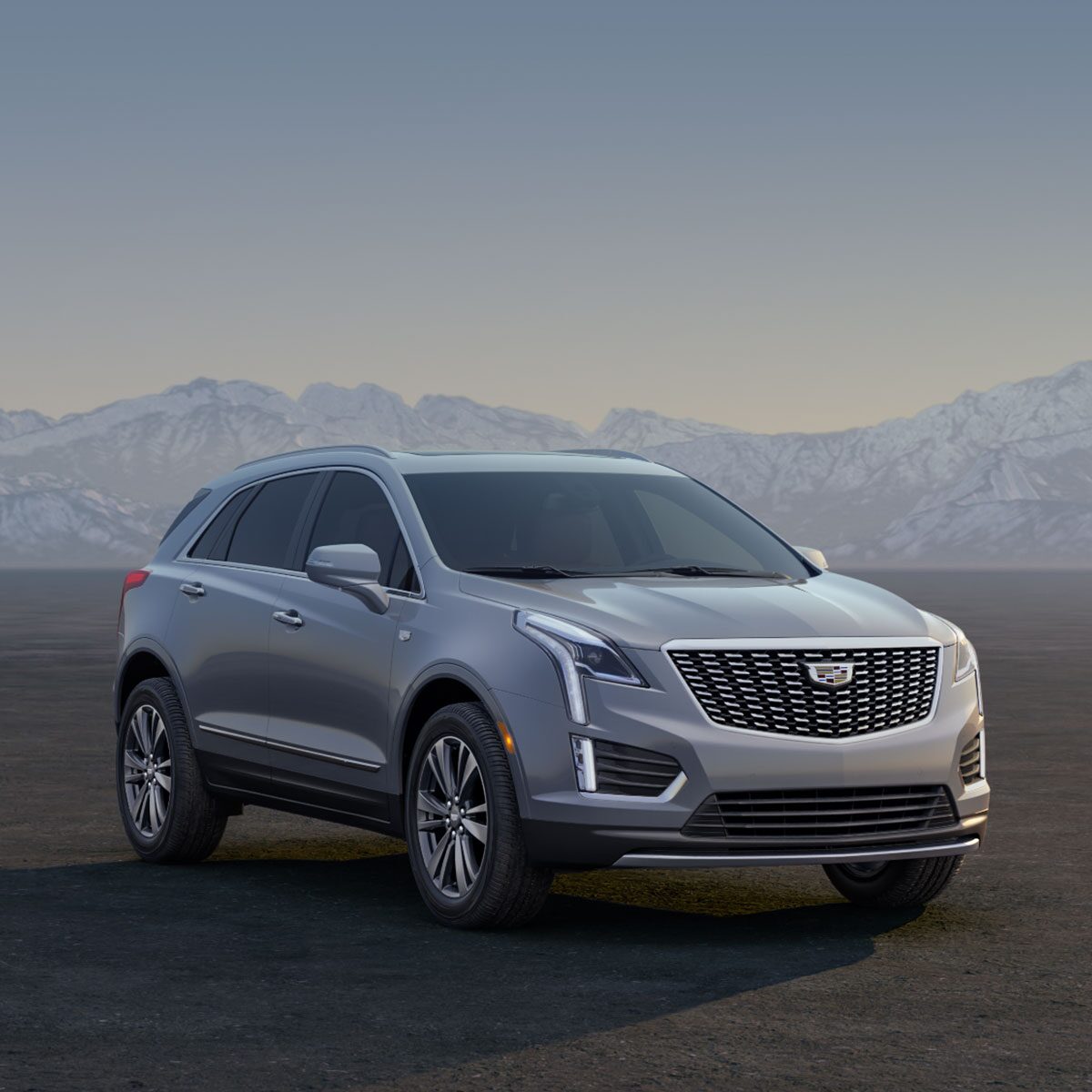 Three Cadillac Silver SUVs Parked on an Open Plain at Sunrise with  Mountains in the Background