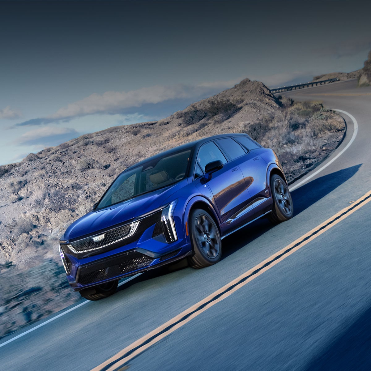 Two Cadillac SUVs Are Parked In a Desert Landscape Beneath Text Announcing Cadillac’s Back-To-Back German Luxury Car Of the Year Win Above the GCOTY Logo.