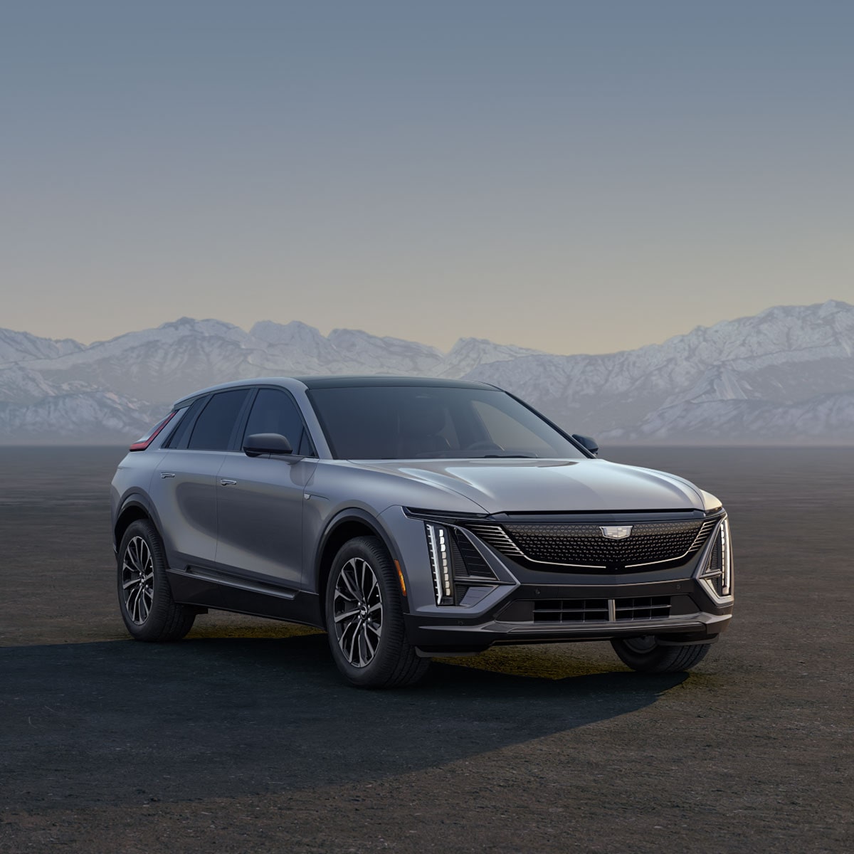 Three Cadillac Silver SUVs Parked on an Open Plain at Sunrise with  Mountains in the Background