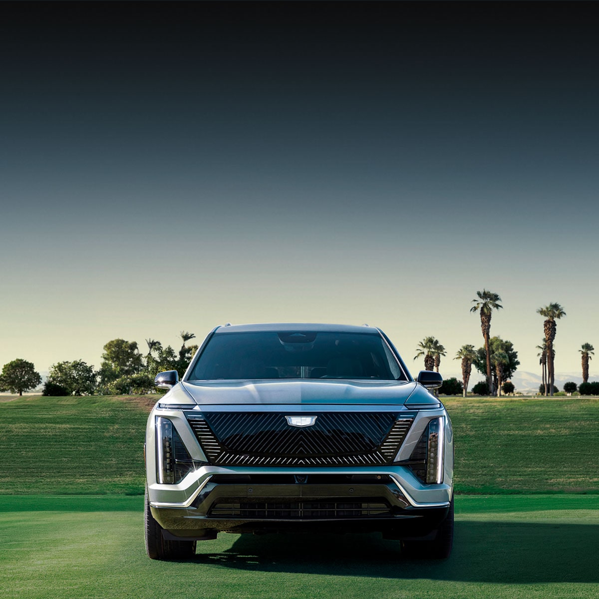A Silver Cadillac LYRIQ V-Series Luxury Sport SUV Driving During Dusk