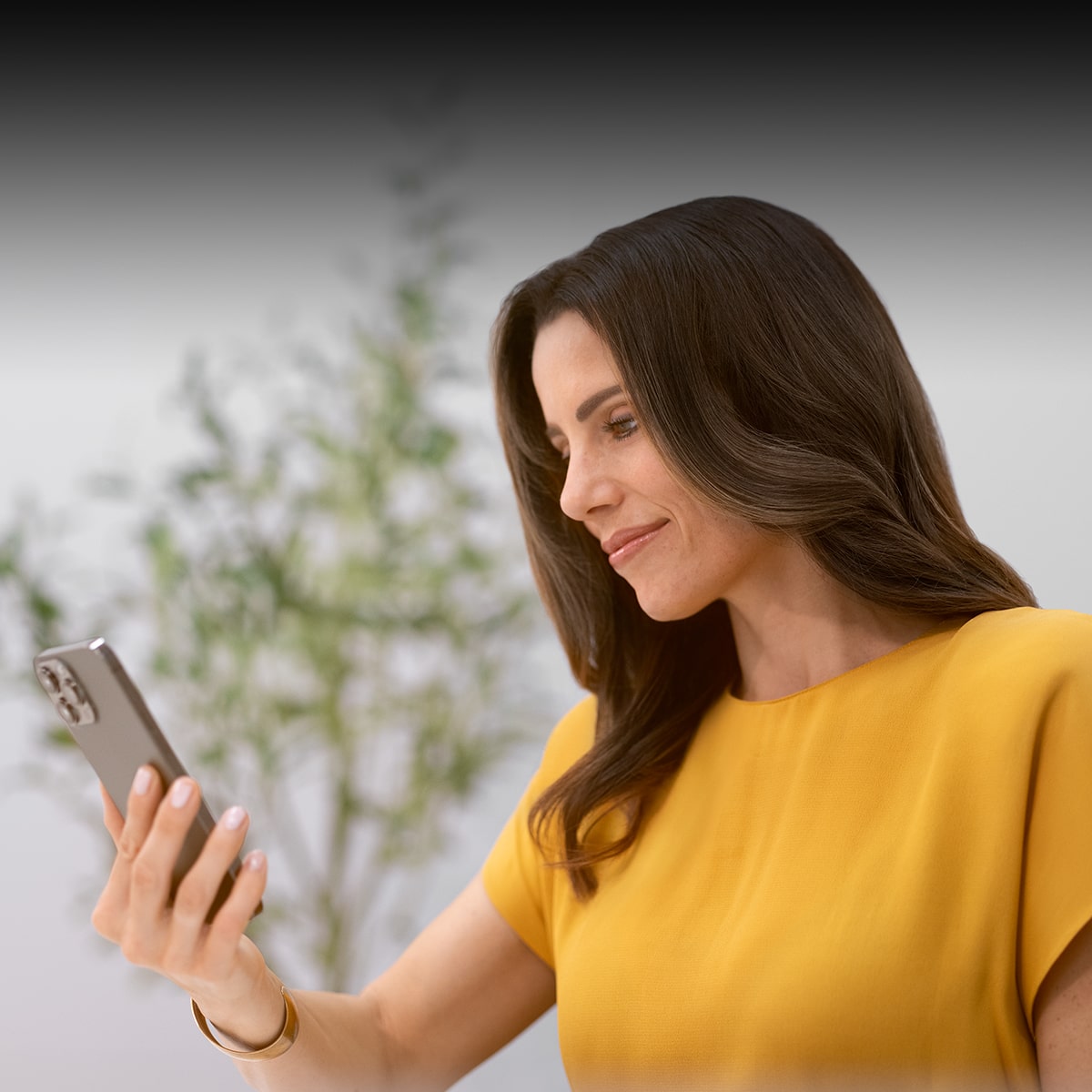 A Woman Smiling and Looking at an iPhone She Is Holding