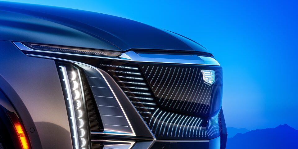 Primer plano de la parrilla y los faros del Cadillac LYRIQ iluminados al anochecer