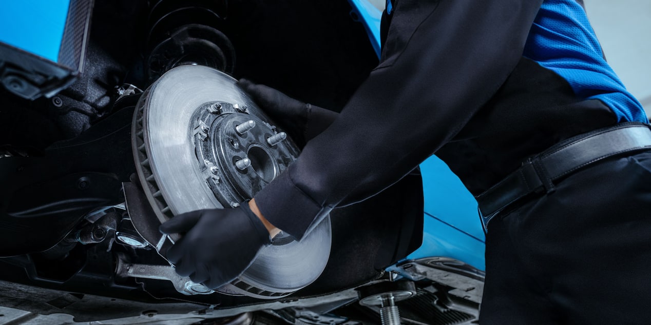 Image of a Service Technician Working on the Tire of a Vehicle to the left of a Brakes and Rotors Rebate Offer 