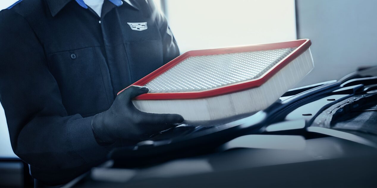 Técnico de Cadillac sosteniendo un filtro de aire de motor