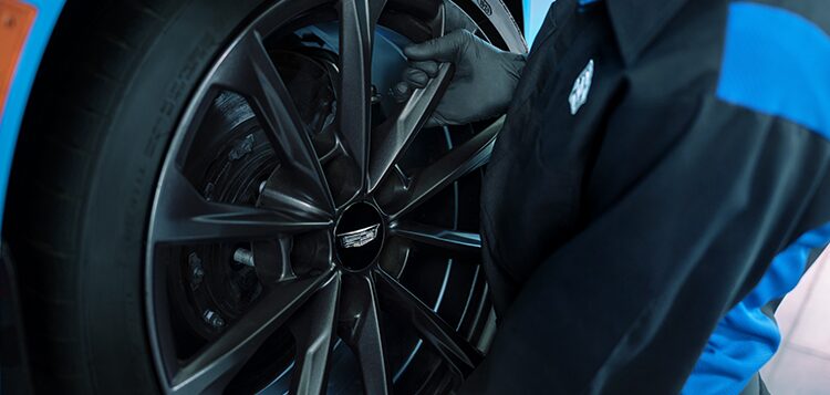 Cadillac Technician Installing a New Wheel on a Vehicle