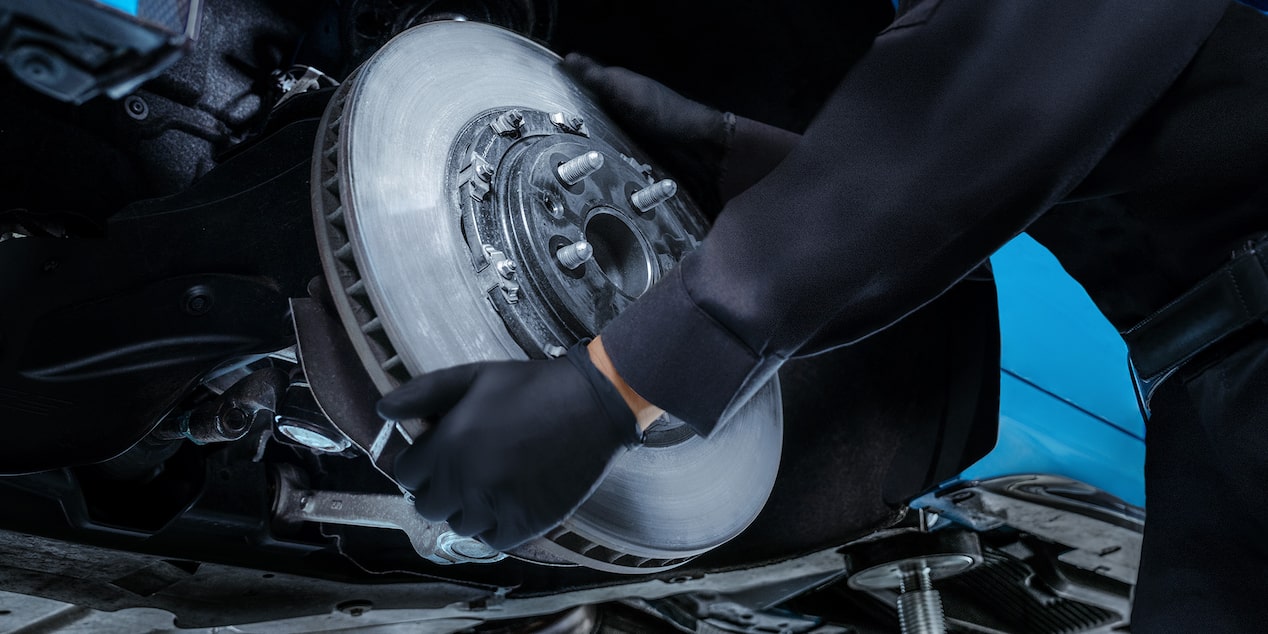 A Mechanics Hands Are Seen Placing a Metal Break Rotor for a Vehicle