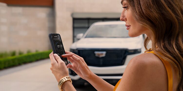 A Woman Using the Cadillac App on Her Phone While Standing Next to Her Vehicle