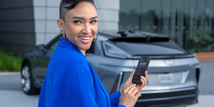 A Woman Using the Cadillac App on Her Phone While Standing Next to Her Vehicle