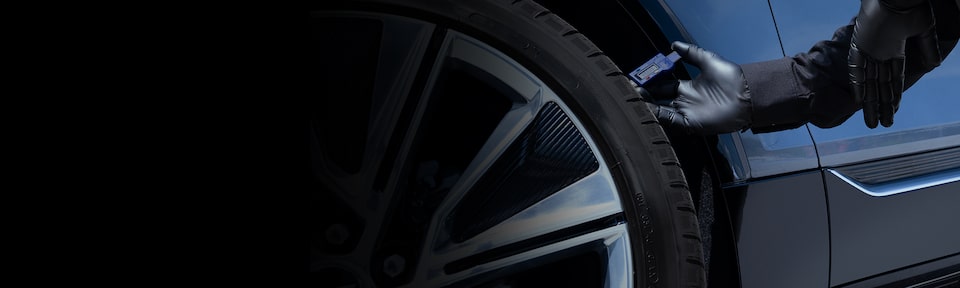 Un técnico del servicio certificado de Cadillac mide el dibujo de los neumáticos de un vehículo