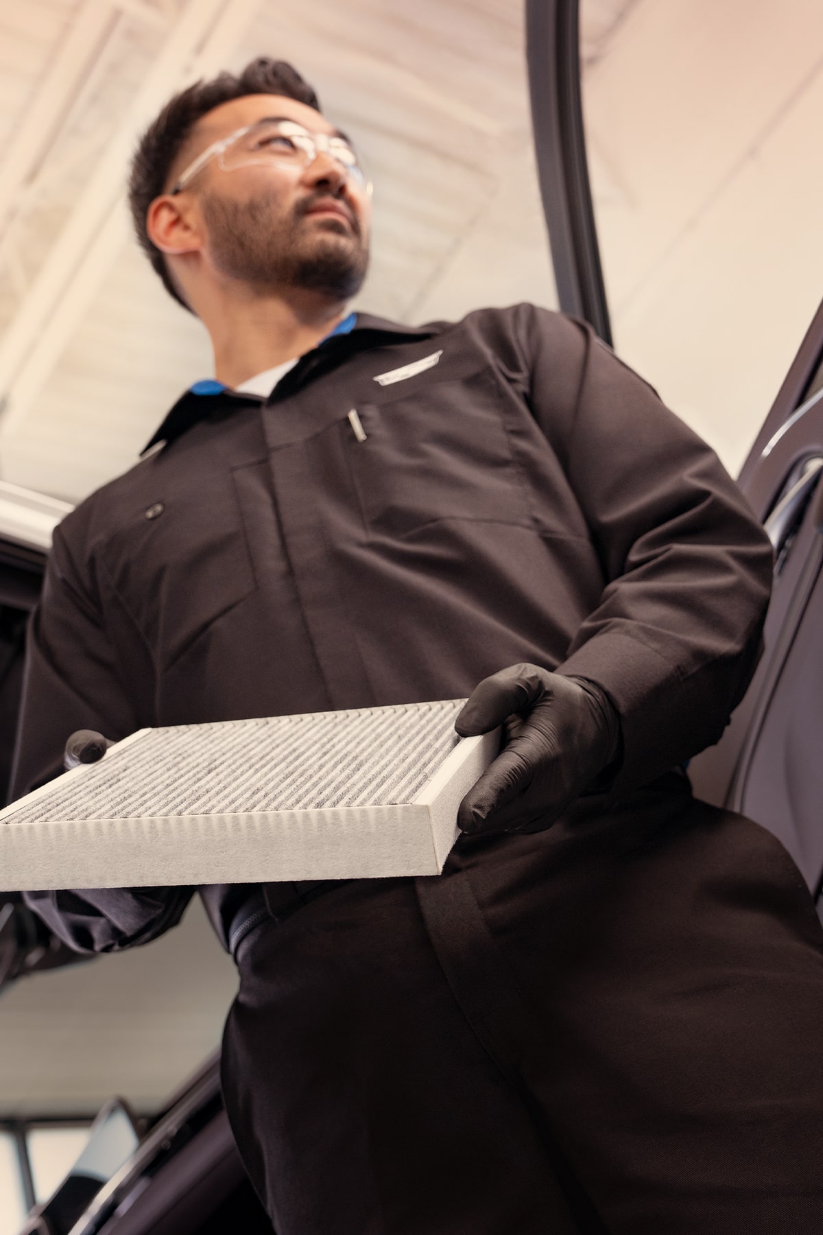 Técnico de servicio certificado de Cadillac sosteniendo el filtro de aire de la cabina de un vehículo